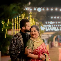 A tender kiss on the forehead under a canopy of warm lights. This intimate moment at their reception captures the deep affection between the couple.