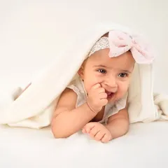 A peek-a-boo smile from under a soft blanket. At six months, babies are so expressive, and I love capturing their playful and shy moments.