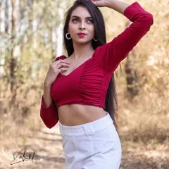 A classic portrait pose set against a beautiful woodland backdrop. The soft, natural light of the golden hour enhances the model's features and the rich colors of her outfit.