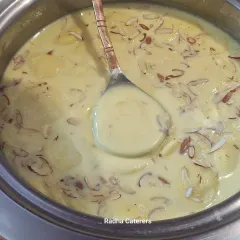 A bowl of rich and creamy Rasmalai, garnished with slivered almonds. This classic Bengali dessert is a popular choice for weddings and festive gatherings.