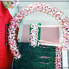 A lovely floral arch made of pink and white roses, set against a green wall for a cradle ceremony. This decoration creates a beautiful frame for the baby's cradle, symbolizing a blessed welcome.