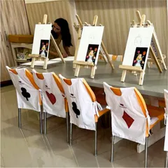 Welcome to Wonderland. For this "Alice in Wonderland" party, we set up individual painting stations with mini easels and custom, hand-painted aprons featuring card suit designs for each little guest.