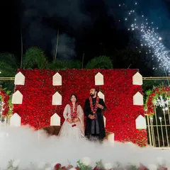 A dramatic reception stage with a bold red rose wall, accented by warm lanterns. The use of theatrical smoke and cold pyro fireworks makes for a truly grand and memorable couple entry.
