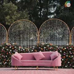 A closer look at the pink velvet sofa against the floral and decorative backdrop. This seating is not only comfortable for the couple but also adds a pop of contemporary color and style to the stage.