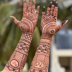 This full-arm engagement mehendi combines traditional motifs with personal touches. You can see the couple's initials and the engagement rings artfully placed within the intricate patterns.