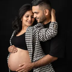 A stylish and intimate portrait of the parents-to-be. Her modern houndstooth blazer and his simple black shirt create a fashionable, coordinated look for their studio maternity session.