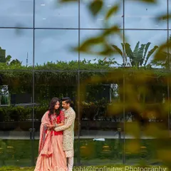 A modern and stylish engagement portrait against a glass-paneled building, capturing the couple in a loving embrace.
