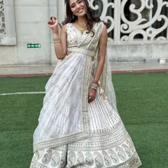 A full-length view of the bride, showcasing the beautifully draped lehenga with a stylish belt.