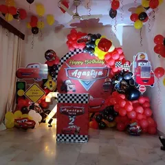 A high-energy Disney Cars theme for a 2nd birthday. This decoration features a checkered flag backdrop, Lightning McQueen cutouts, a marquee number '2', and a red and black balloon arch to create a racetrack feel right at home.