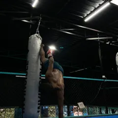 Combining skills for a unique challenge. Here, a trainer performs a one-arm handstand while using a punching bag for support. This is an extreme display of balance, core stability, and shoulder strength.