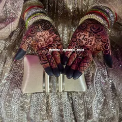 The bride's hands, adorned with intricate mehendi, colorful bangles, and holding a clutch. This is the complete party look.