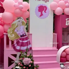 A life-sized Barbie cutout poses on a custom-built pink staircase, creating a perfect photo spot.