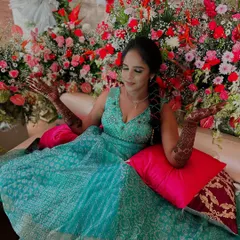 This bride looks radiant, surrounded by flowers that complement her beautiful mehndi. Capturing these moments of joy is what it's all about.