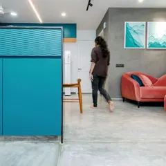 A view from the kitchen pass-through into the living area, showcasing the dynamic interplay of teal, blush, and grey tones.