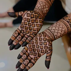 A close-up view of a detailed grid pattern, also known as 'jaali' work. This technique creates a beautiful net-like effect that is a hallmark of traditional bridal henna.