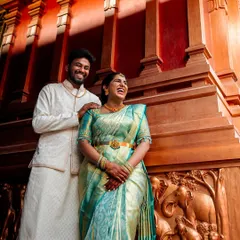 A candid laugh during an engagement shoot. The rich wooden backdrop with elephant carvings adds a traditional touch to this vibrant, happy portrait.