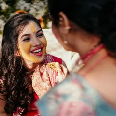 A beautiful candid moment of laughter during a Haldi ceremony. The genuine smile and smear of turmeric paste tell a happy story.