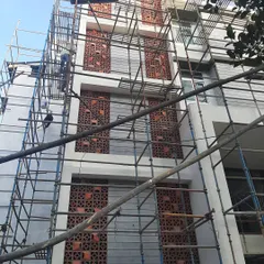 The staircase wall of a building under construction, with terracotta jali screens being installed. This image captures the labor and craftsmanship involved in creating these sustainable and decorative architectural elements.