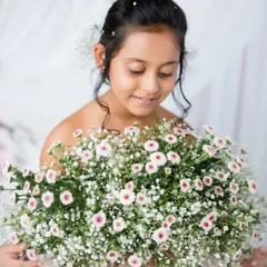 A close-up shot, focusing on her sweet expression as she holds a large bouquet of flowers.