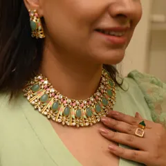 A client trying on a stunning green and pink necklace set. This close-up shows the intricate craftsmanship and beautiful color combination, perfect for adding a regal touch to a festive outfit.