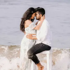 An intimate portrait of a couple by the sea, with waves crashing around them. This photo focuses on their close embrace and the romantic atmosphere of the beach.