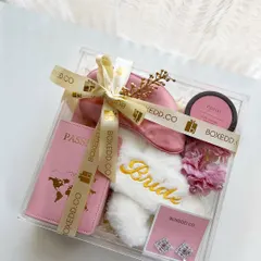 Forget the old shagun ka lifafa. This modern acrylic gift box for the bride-to-be is filled with travel essentials like a passport cover, comfy 'Bride' slippers, a silk eye mask, and jewelry.