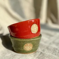 A pair of small bowls in festive red and green, each with a gold snowflake emblem. These are great for serving dips or holding little trinkets.