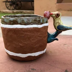 A custom mug with a story. This piece has a textured, earthy body and a whimsical, hand-sculpted bird handle that seems to be offering a little heart. It makes your morning coffee a bit more magical.
