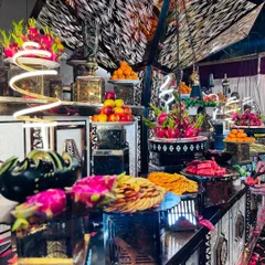 A lavish and dramatic fruit display, featuring tiers of exotic fruits like dragon fruit, apples, and oranges. The intricate black and silver counter design makes this a stunning centerpiece.