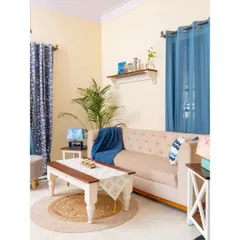 This farmhouse-inspired living room combines a comfortable tufted sofa with a classic white and wood coffee table. The use of natural materials like jute and wood creates a cozy, earthy atmosphere.