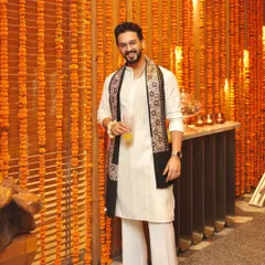 A full-length view of the elegant Diwali look. The classic off-white kurta is paired with flared white pants and an embroidered stole, creating a sophisticated and festive ensemble.