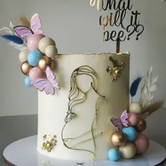 A beautiful and modern baby shower cake. The "What will it bee?" theme is subtly hinted at, with a line-art illustration of a mother-to-be, and a soft color palette of pastels and gold.