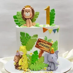 A cute jungle theme cake for a first birthday, with a friendly lion, giraffe, and elephant. All the animal figures are handmade and edible.