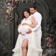 A classic portrait against a dark, floral-adorned archway. The couple is dressed in white, creating a beautiful contrast that makes the moment feel timeless and painterly.