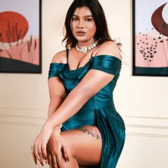 This is a powerful, glamorous portrait. The pose, with the high-slit teal satin dress, is confident and strong, and the studio lighting perfectly highlights the texture of the fabric.
