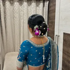 An elegant bridal bun, adorned with fresh purple and white orchids. This classic hairstyle is perfect for a sophisticated wedding or reception look.
