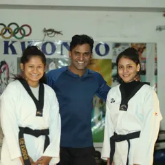 Posing with two of my black belt students in our dojang. I work closely with advanced students to refine their technique and prepare them for leadership roles.