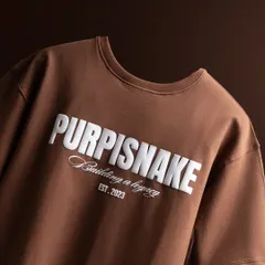 A clean, angled shot of the t-shirt, focusing on the neckline and the bold branding. The lighting is soft and even to show the true color of the fabric.