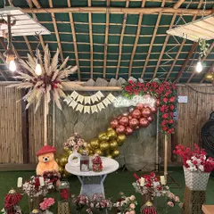 We love a rustic birthday theme. This setup at Sarpanch Bagh in Noida features a "Lets Party" neon sign, a mix of red and gold balloons, pampas grass arrangements, and plenty of floral details for a warm and festive feel.