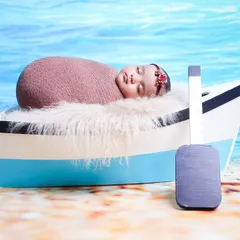 Setting sail on a new adventure with this nautical-themed photoshoot. The baby is safely swaddled in a miniature boat prop against a bright beach and ocean backdrop.