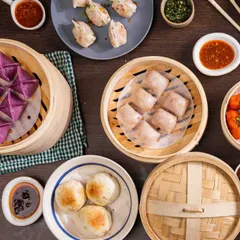 A top-down view of a diverse dim sum spread. You can see various types, from purple and pink steamed dumplings to pan-fried gyoza, showcasing the variety I offer for any gathering.