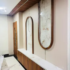 An entrance console and wall panel during installation. This photo shows the raw wood and marble-finish materials being fitted, highlighting the solid construction of the custom furniture.