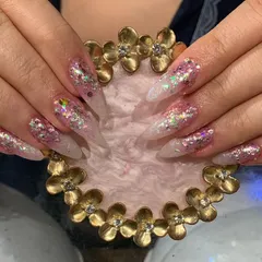 An explosive mix of holographic and iridescent chunky glitter over a sheer base on long stiletto nails.