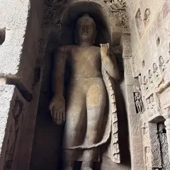 A colossal standing Buddha statue carved into the rock face at Kanheri Caves, showcasing the scale and devotion of the artisans.
