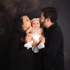 Kisses for the little one. This heartwarming family portrait captures the love and affection of parents for their baby girl, creating a truly precious memory.