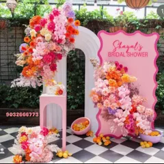 For this bridal shower, I designed a vibrant floral backdrop using a mix of bright orange, pink, and yellow artificial flowers. The custom pink arched panels and matching pedestal for the cake complete this cheerful and modern look.