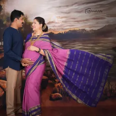 A fine-art studio portrait inspired by the paintings of Raja Ravi Varma. The couple is posed against a painted backdrop, creating a timeless and artistic image.