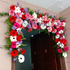 A main door decoration using an arch of fresh, colorful gerbera daisies. This vibrant floral arrangement is perfect for housewarmings or festive occasions.