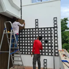 A closer view of the installation in progress. One of my team members is on a ladder, fixing the final sections of the grid to the wall. This durable framework is essential for supporting the weight of the plants and the irrigation system.