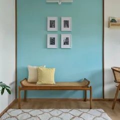 The home office in our 'Malhar' project features a serene blue accent wall, a comfortable cane bench, and a matching chair. The space is designed to be both calming and inspiring.